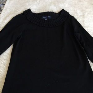 A black ruffled neck, long sleeve, all black shirt